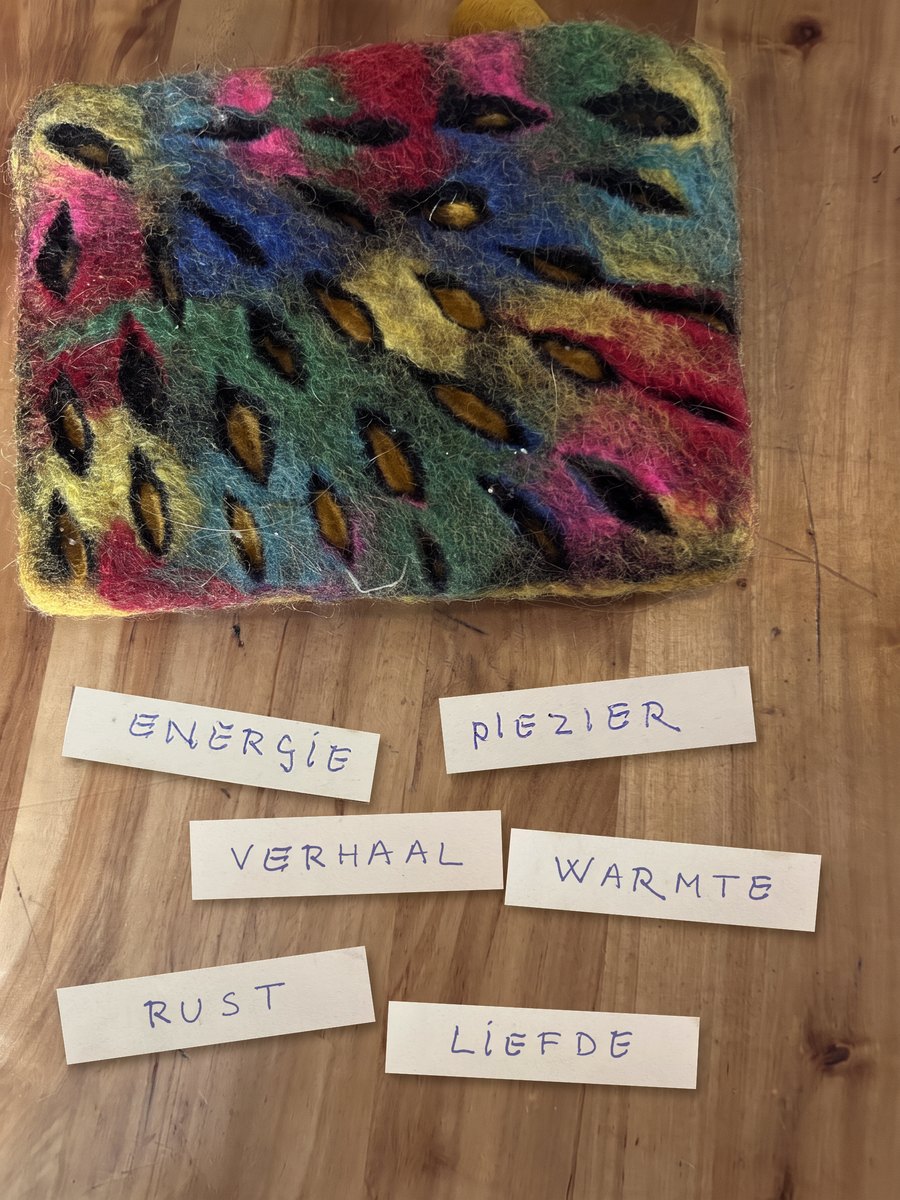 Anne's felt bag in pink, blue, green and yellow wool, with her six handwritten wish cards on the table: energie, plezier, verhaal, warmte, rust and liefde